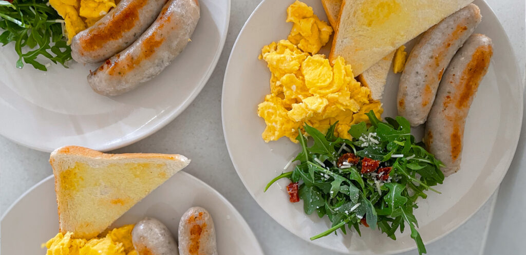 Breakfast Ideas for Physical active individuals - Plate of breakfast featuring scrambled eggs, sausages, toast, rocket and parmesan cheese salad